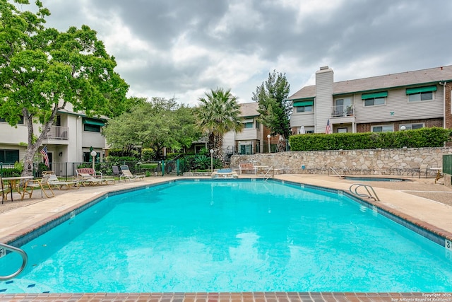 community pool featuring fence, a residential view, and a patio