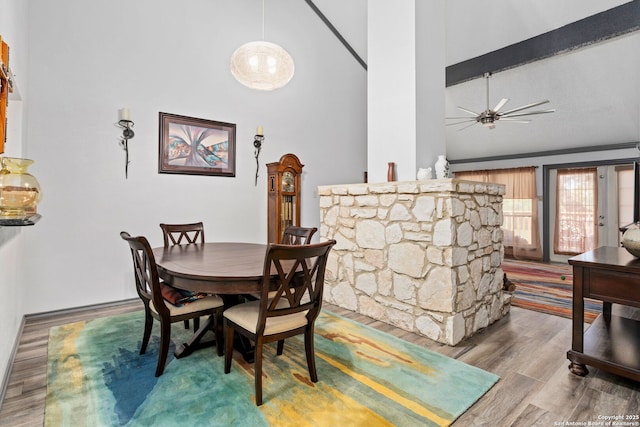 dining space with wood finished floors, high vaulted ceiling, and ceiling fan