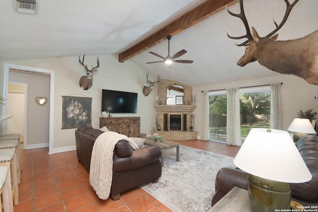 tiled living area featuring lofted ceiling with beams, baseboards, visible vents, a brick fireplace, and ceiling fan