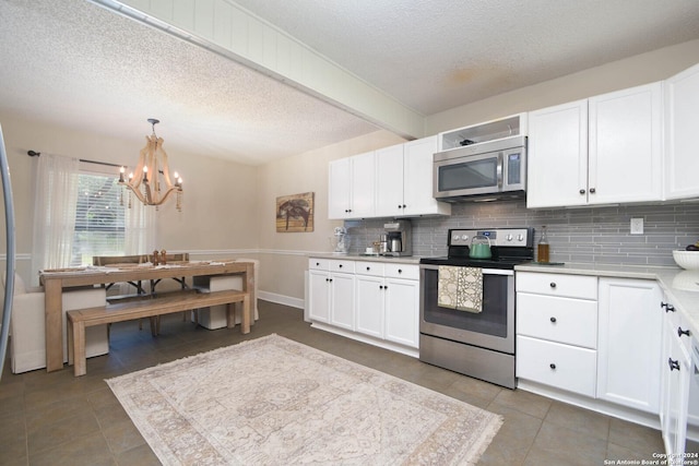 kitchen with tasteful backsplash, a textured ceiling, tile patterned floors, stainless steel appliances, and a notable chandelier