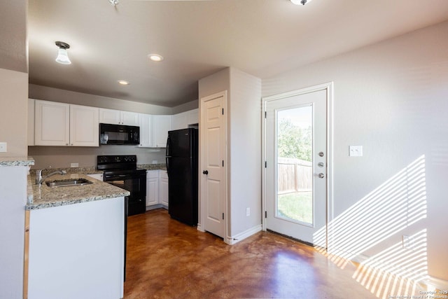 kitchen with a sink, light stone countertops, black appliances, concrete floors, and white cabinetry