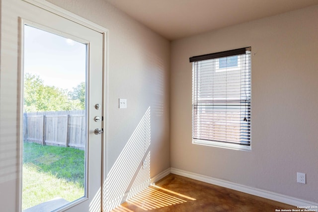 doorway with a wealth of natural light, baseboards, and finished concrete floors
