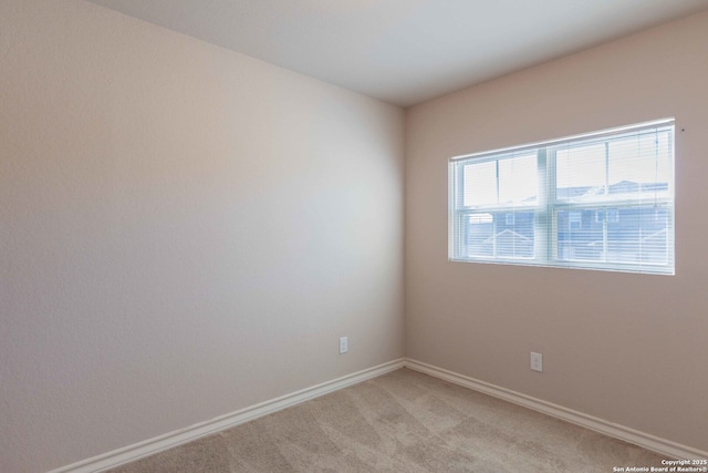 spare room featuring baseboards and light colored carpet