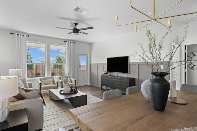 living area with wainscoting, ceiling fan, wood finished floors, and visible vents