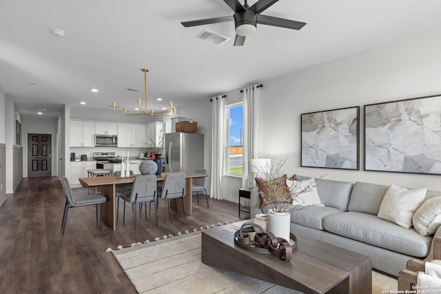 living room featuring ceiling fan with notable chandelier, visible vents, recessed lighting, and dark wood-type flooring