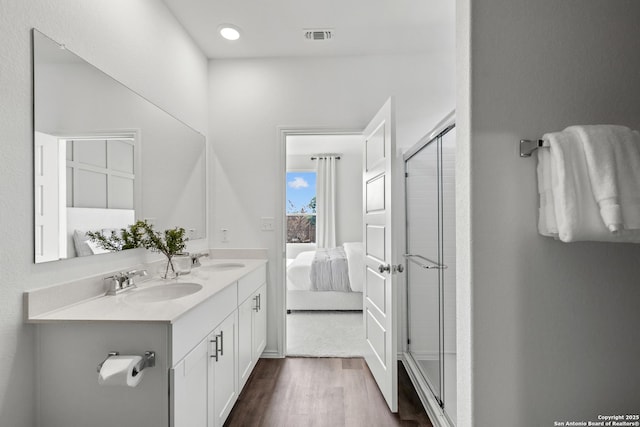 bathroom with ensuite bathroom, wood finished floors, a sink, and a shower stall