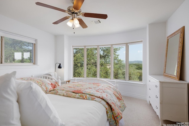 bedroom with visible vents, light carpet, a ceiling fan, and multiple windows
