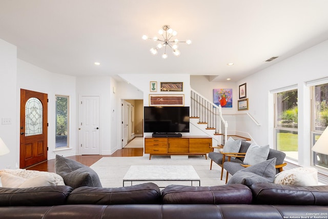 living area with light wood-style floors, visible vents, a wealth of natural light, and stairs