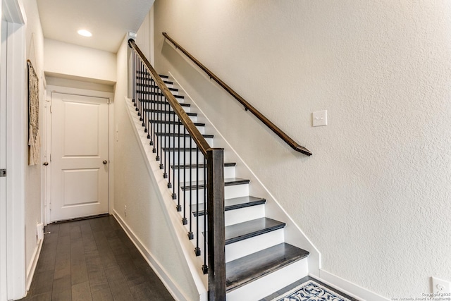 stairway with a textured wall, baseboards, and wood finished floors