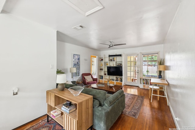 living room with attic access, visible vents, baseboards, a ceiling fan, and wood finished floors