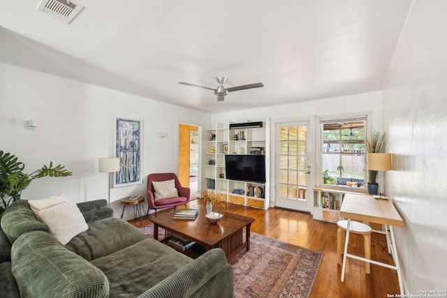 living room featuring wood finished floors, visible vents, and ceiling fan