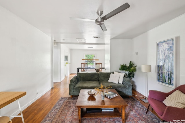 living area with visible vents, baseboards, wood finished floors, and ceiling fan