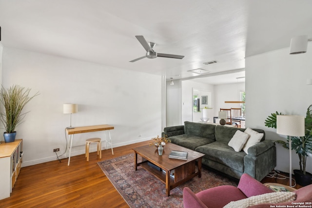 living area with wood finished floors, visible vents, a ceiling fan, baseboards, and attic access