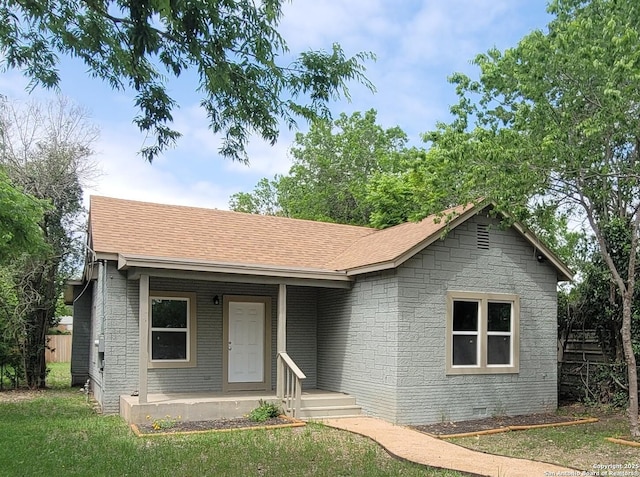 view of front of house featuring brick siding, roof with shingles, and a front lawn