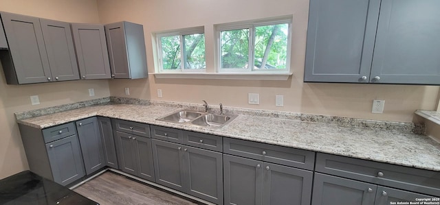 kitchen featuring wood finished floors, light countertops, gray cabinetry, and a sink