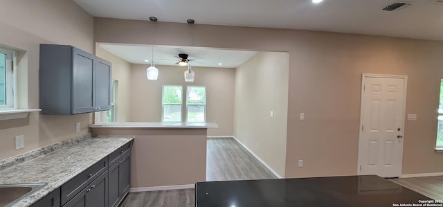 kitchen with ceiling fan, a peninsula, wood finished floors, and visible vents