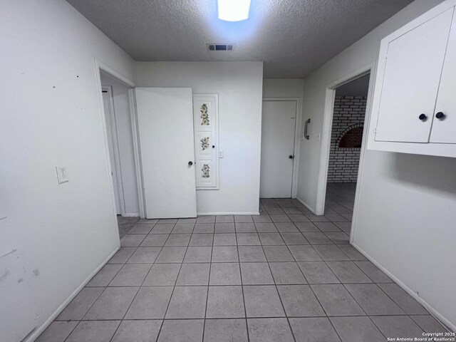 7 Sunrise, Pleasanton, TX 78064 - hall with baseboards, light tile patterned flooring, a textured ceiling, and visible vents