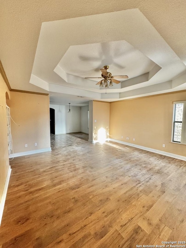 36 Leona Hts, Uvalde, TX 78801 - spare room with a tray ceiling, a ceiling fan, light wood-style flooring, baseboards, and a textured ceiling