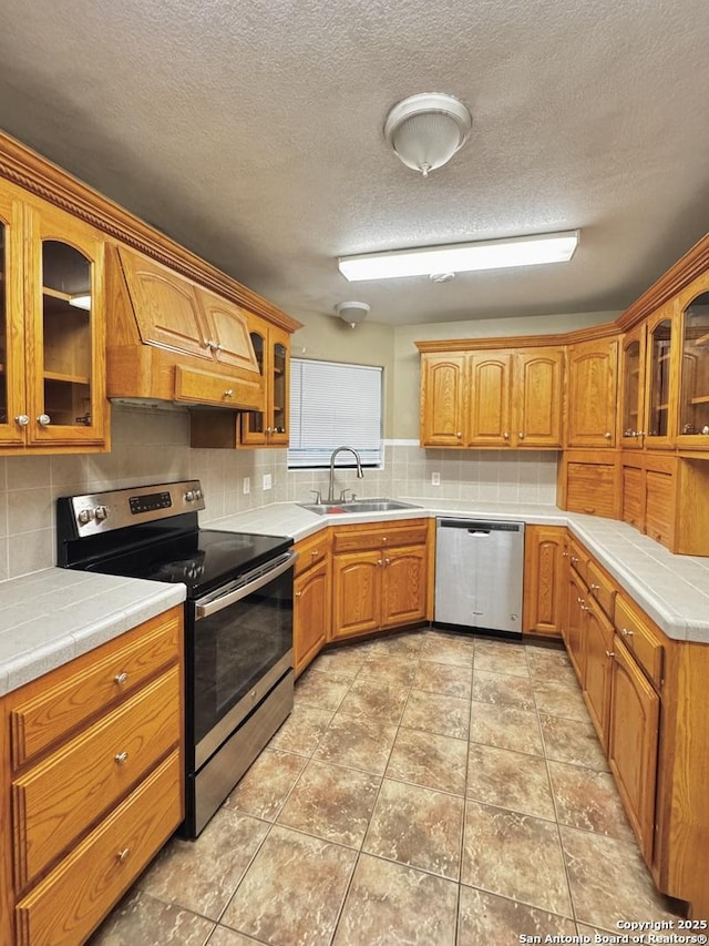 36 Leona Hts, Uvalde, TX 78801 - kitchen with appliances with stainless steel finishes, a sink, backsplash, premium range hood, and a textured ceiling