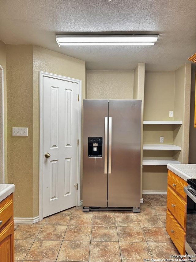 36 Leona Hts, Uvalde, TX 78801 - kitchen with stainless steel fridge, a textured wall, a textured ceiling, light countertops, and range