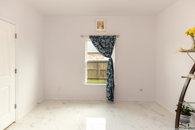 empty room featuring marble finish floor and baseboards
