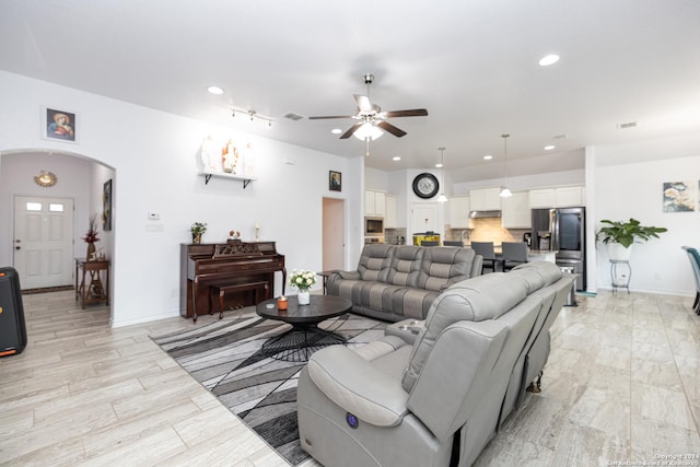 living room with ceiling fan, arched walkways, baseboards, and recessed lighting