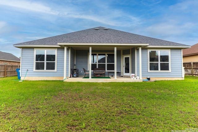 rear view of property featuring a lawn, a shingled roof, a patio, and fence