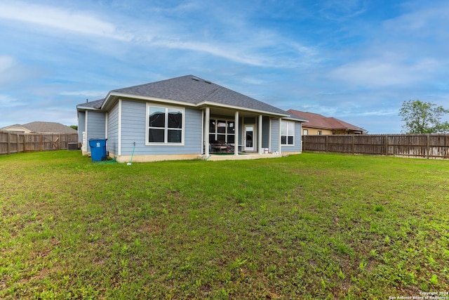 rear view of property featuring a fenced backyard, a patio area, a shingled roof, and a lawn