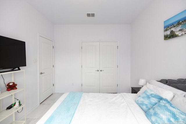bedroom featuring visible vents, marble finish floor, and a closet