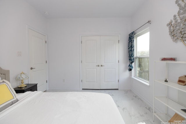 bedroom featuring baseboards, marble finish floor, and a closet
