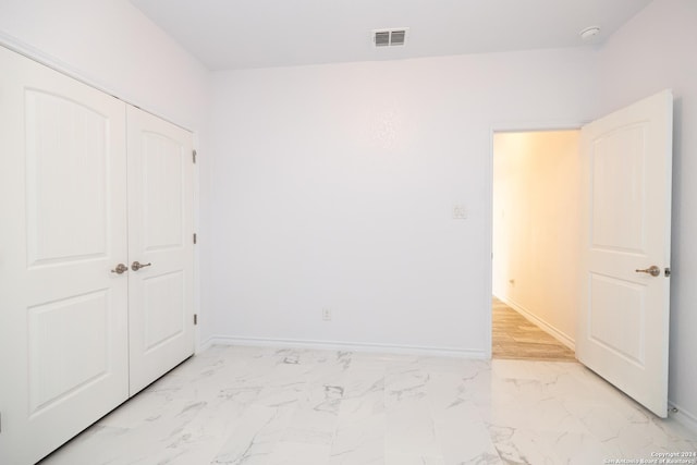unfurnished bedroom with a closet, visible vents, marble finish floor, and baseboards