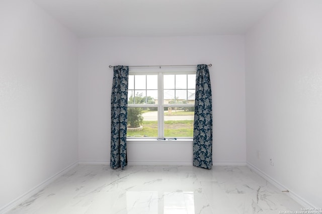spare room with marble finish floor and baseboards