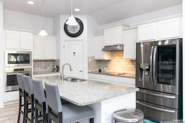 kitchen with a sink, a breakfast bar, stainless steel appliances, white cabinetry, and under cabinet range hood
