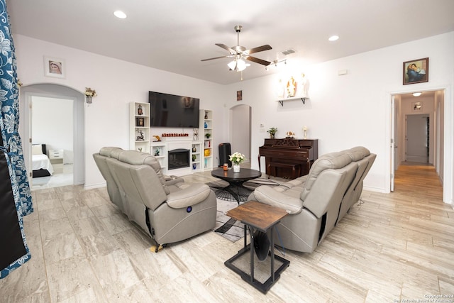 living area featuring ceiling fan, arched walkways, a fireplace, visible vents, and recessed lighting