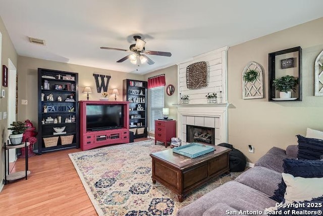 living area featuring ceiling fan, visible vents, wood finished floors, and a fireplace