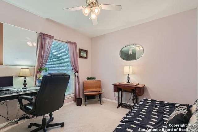 carpeted office featuring baseboards and a ceiling fan