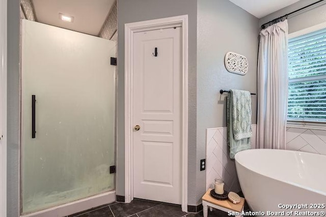 full bathroom featuring tile patterned floors, a soaking tub, and a shower stall