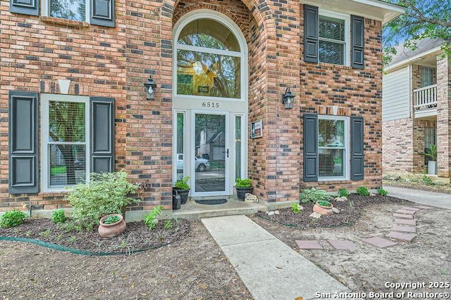 view of exterior entry featuring brick siding