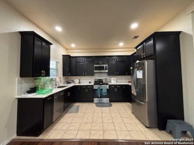 1121 N Oak, Pearsall, TX 78061 - kitchen with decorative backsplash, appliances with stainless steel finishes, light countertops, dark cabinets, and recessed lighting