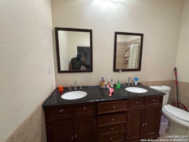 1121 N Oak, Pearsall, TX 78061 - bathroom with double vanity, toilet, a textured wall, and a sink
