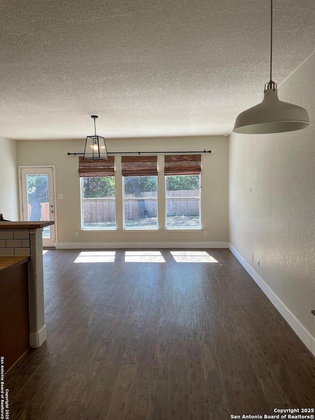 unfurnished dining area featuring baseboards and dark wood-type flooring