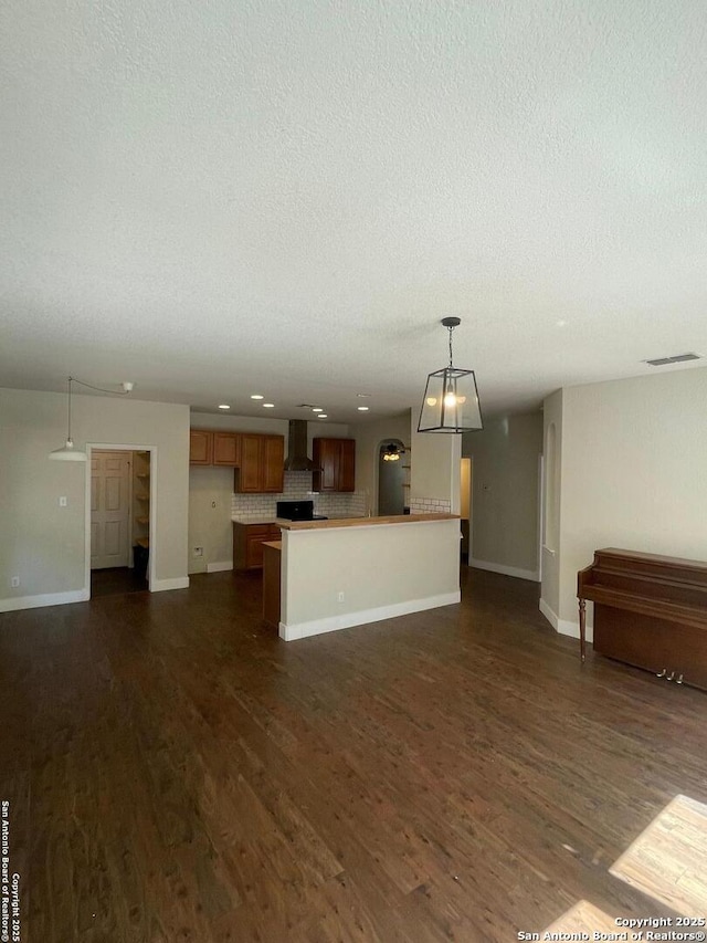 unfurnished living room with dark wood finished floors, baseboards, a textured ceiling, and visible vents