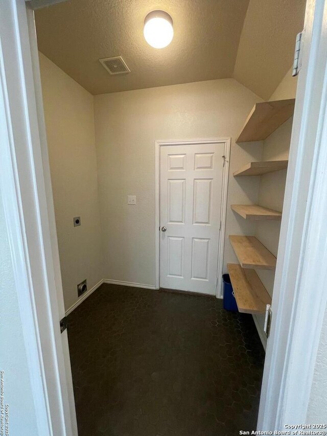 laundry area with laundry area, dark colored carpet, visible vents, electric dryer hookup, and a textured ceiling