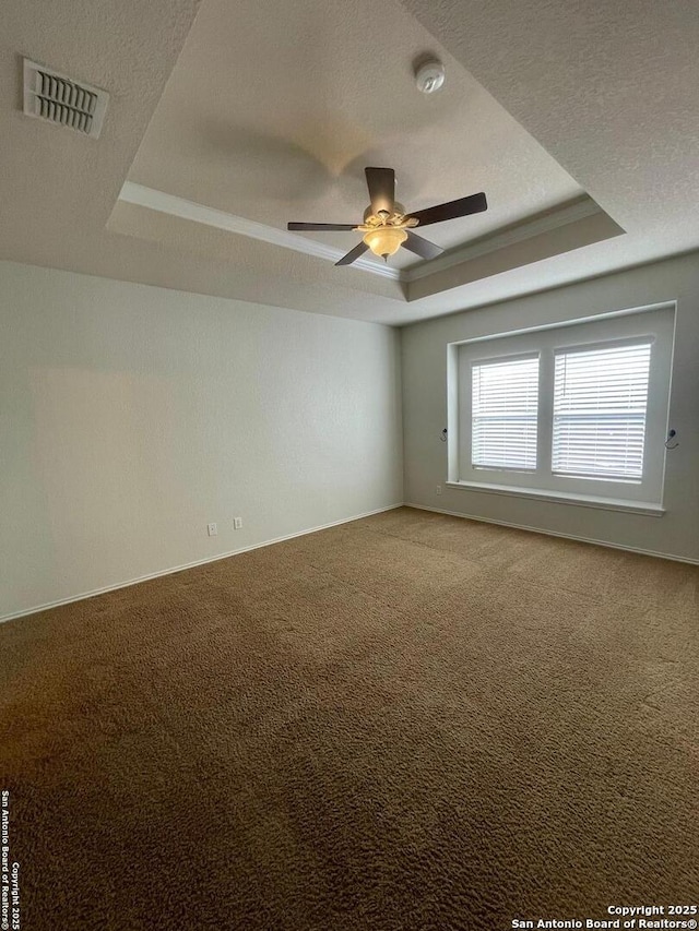 unfurnished room with a ceiling fan, a textured ceiling, light carpet, a tray ceiling, and visible vents