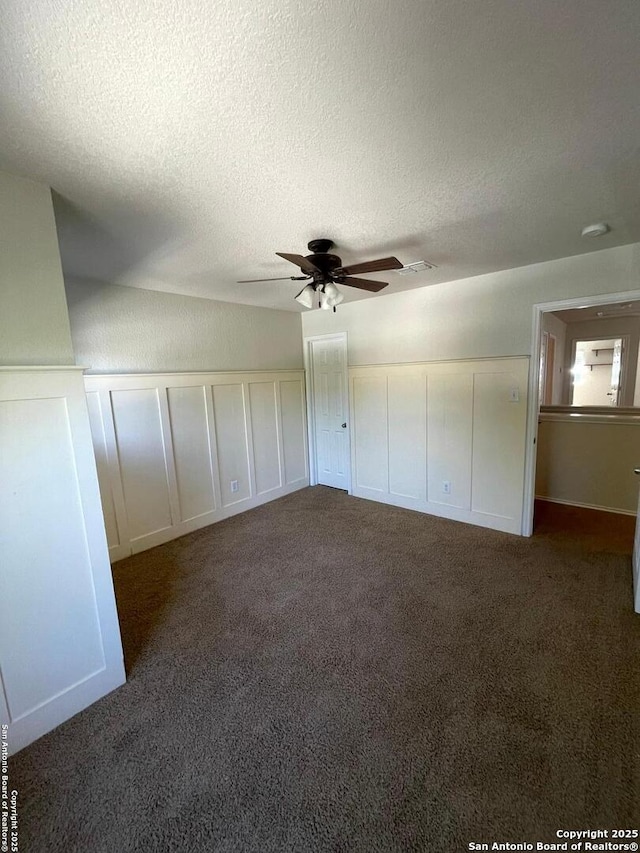 unfurnished bedroom featuring a textured ceiling, carpet floors, and a decorative wall