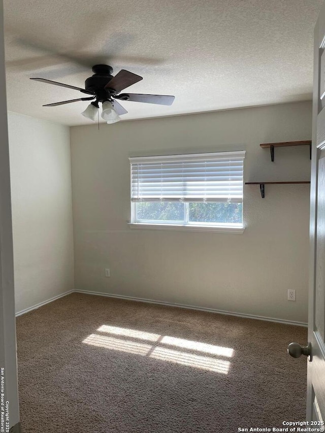 carpeted empty room featuring a textured ceiling, a ceiling fan, and baseboards