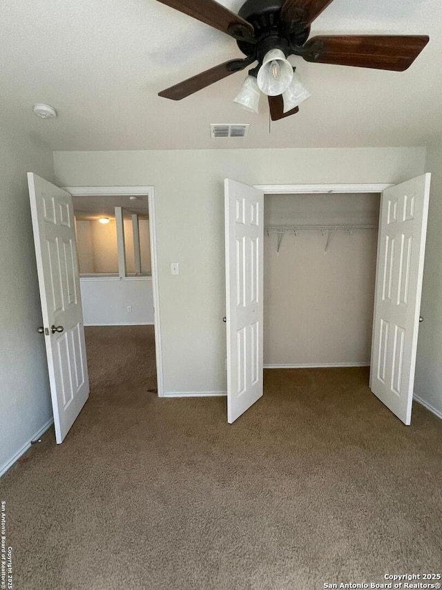 unfurnished bedroom with a closet, ceiling fan, carpet floors, baseboards, and visible vents