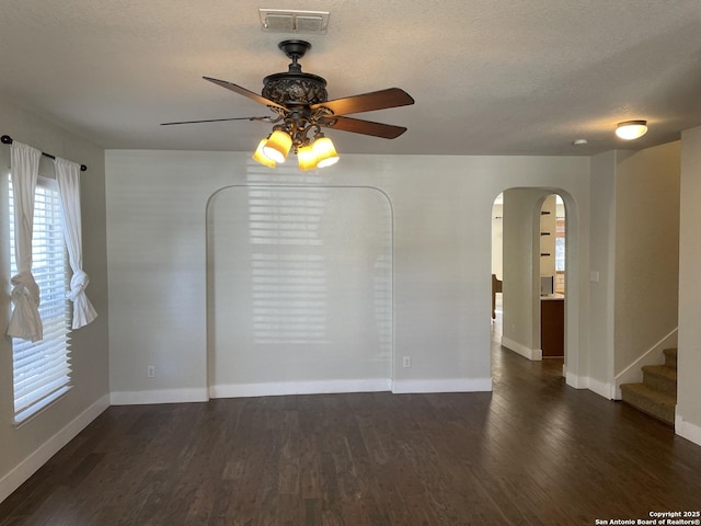 unfurnished room featuring arched walkways, wood finished floors, visible vents, and ceiling fan