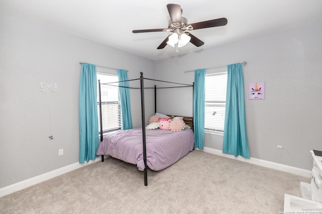 bedroom with ceiling fan, baseboards, light colored carpet, and multiple windows