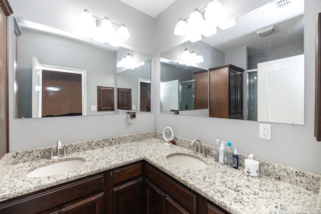bathroom with double vanity, visible vents, a stall shower, and a sink